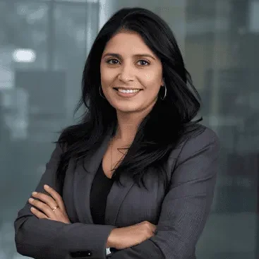 Laura P Confident professional woman in a blazer, smiling with arms crossed.