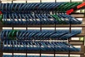 Cat6 Ethernet Network patch panel with organized blue and green cables interconnected.
