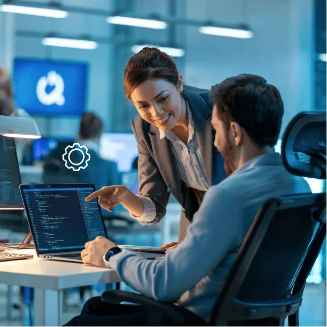 Colleagues discussing coding on a laptop in a modern office setting.