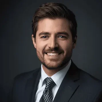 David M Smiling man in a suit with short hair, set against a dark background.