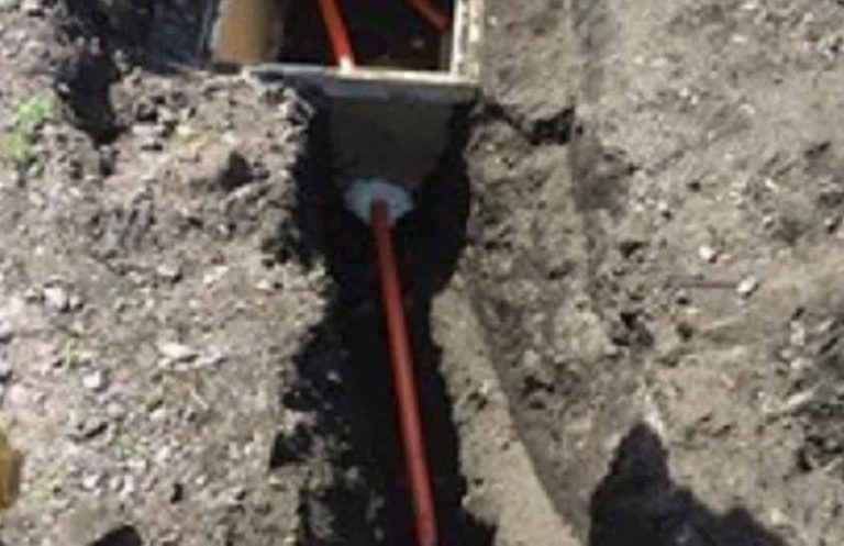 commercial fiber optic installation with Trench in dirt with orange utility conduit visible