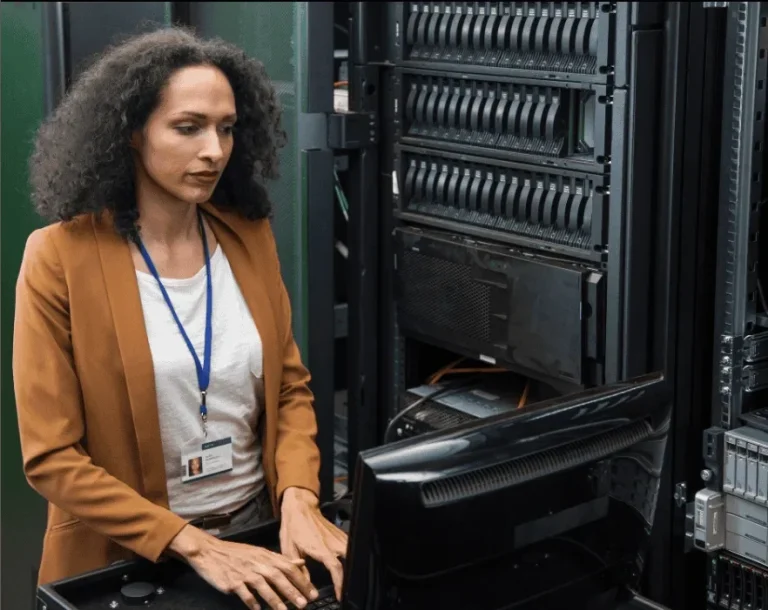 A woman in professional attire working on server equipment in a data center.