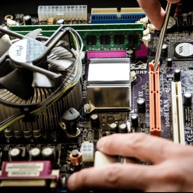 A person using a tool to work on a computer motherboard.